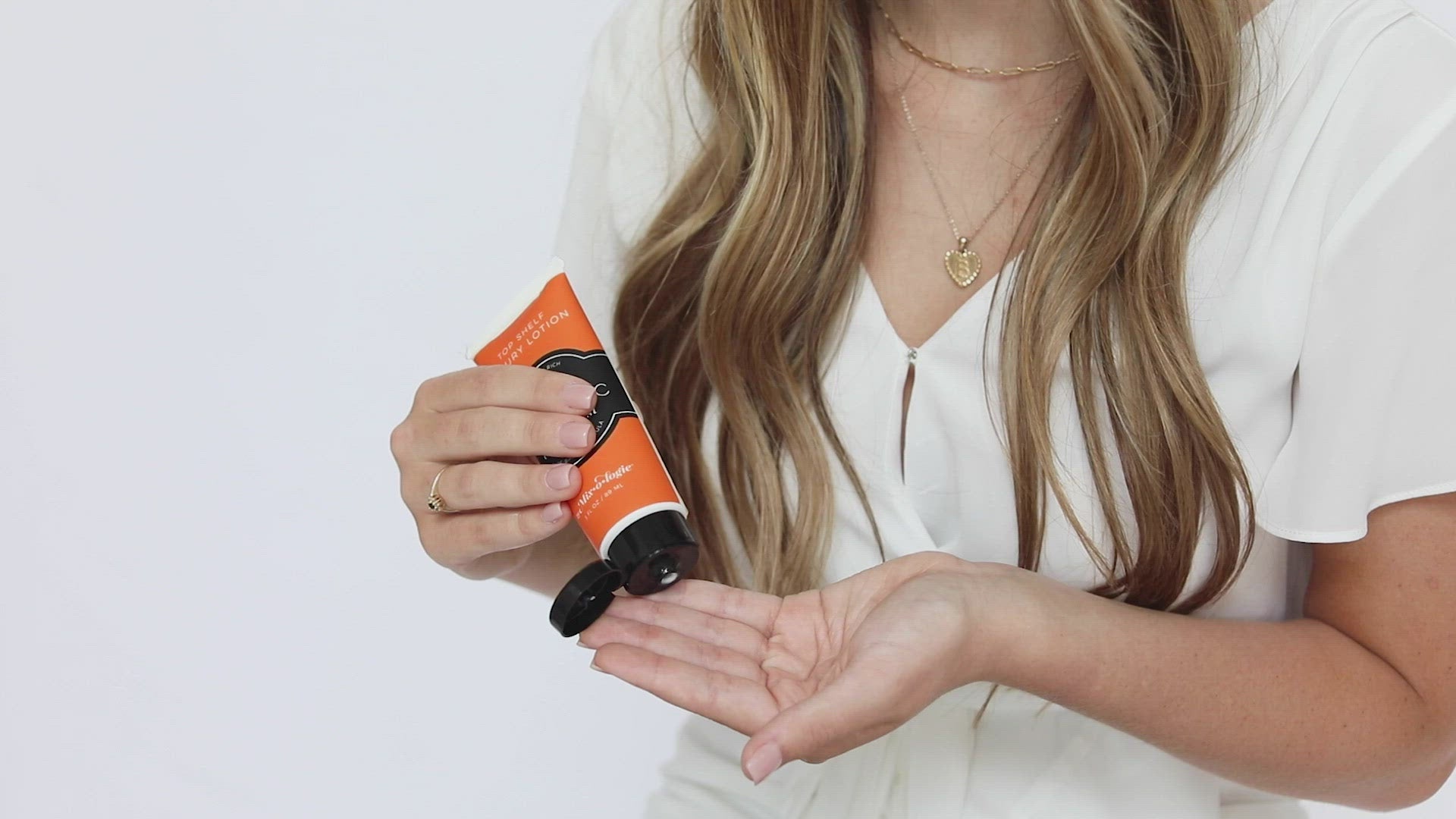Electric (Citrus Twist) Top Shelf Lotion in orange tube with black lid and label. Nutrient rich, aloe-based formula, tube has 5 fl oz or 89 mL. Pictured with model applying to hands and smelling the scent then smiling.