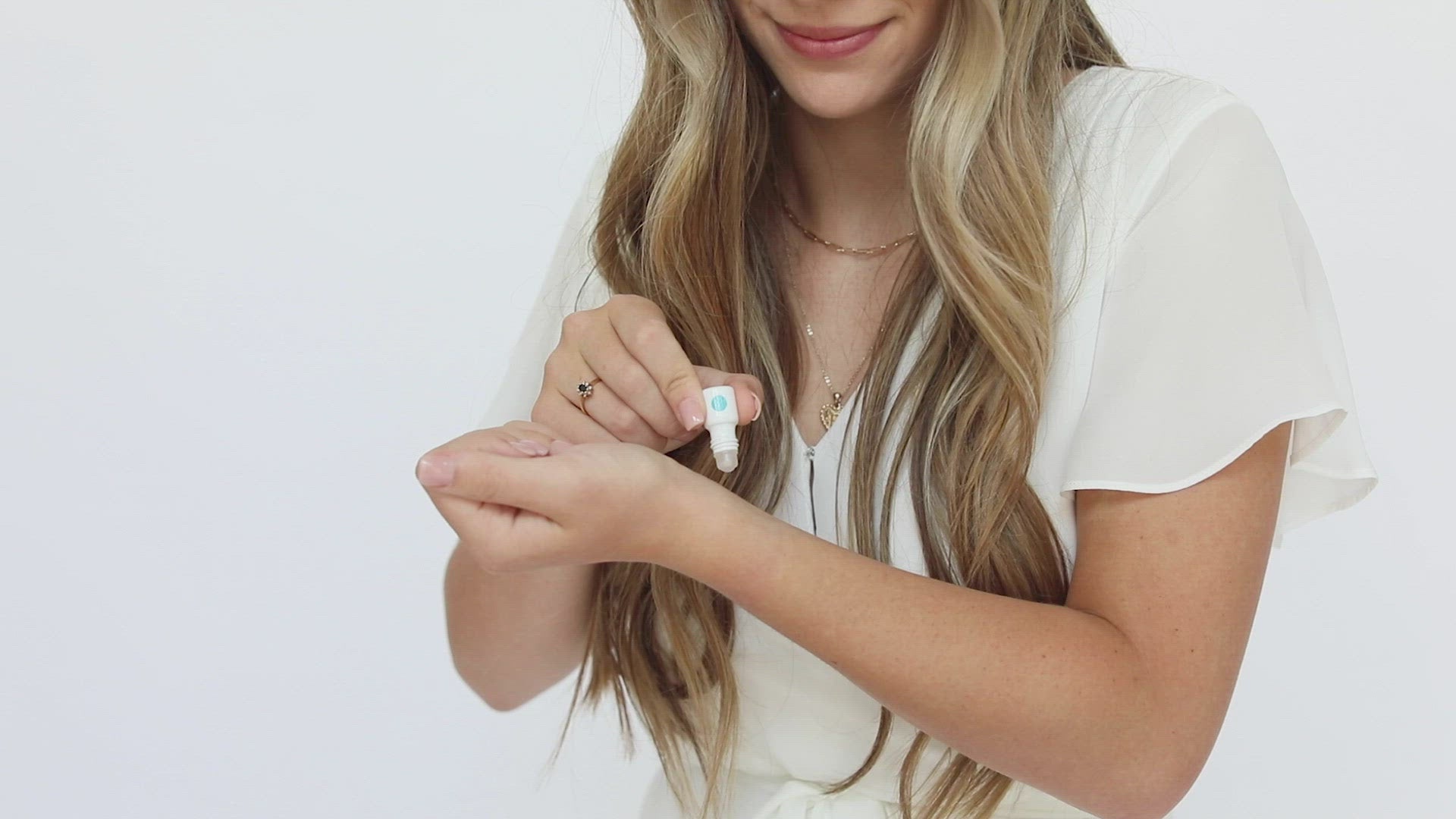 Randi – Tender Wrist Application: Tender (Fruity) mini white cylinder rollerball with bright blue pattern has .035 fl oz or 1 mL. Mini rollerball being applied to model’s wrist.