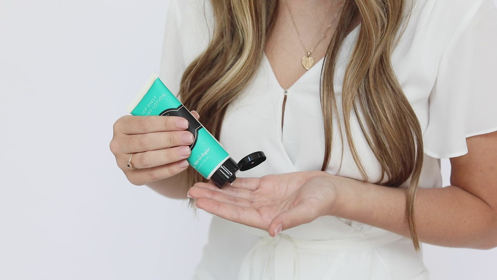 Tender (Fruity) Top Shelf Lotion application by model. Model squeezes a dime size bit of lotion into her hand and rubs onto hands then smells her hand and smiles.