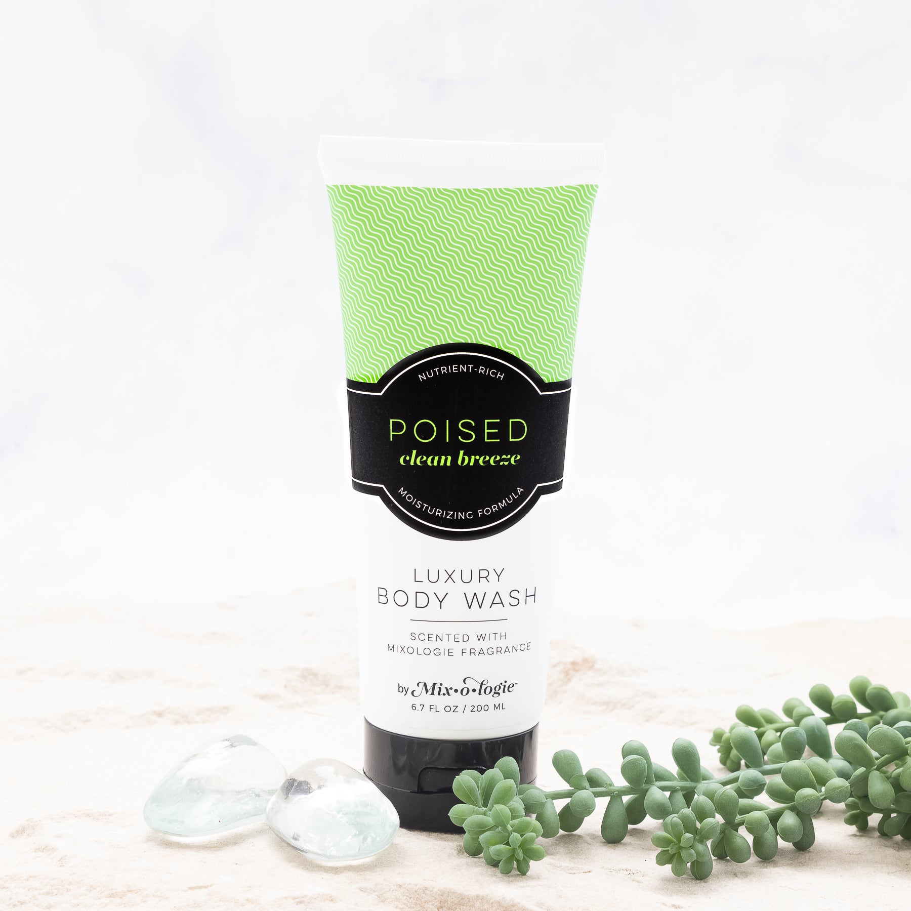 Luxury Body Wash of Poised (Clean Breeze) in light green pattern package and black label with sand, rocks, and greenery.