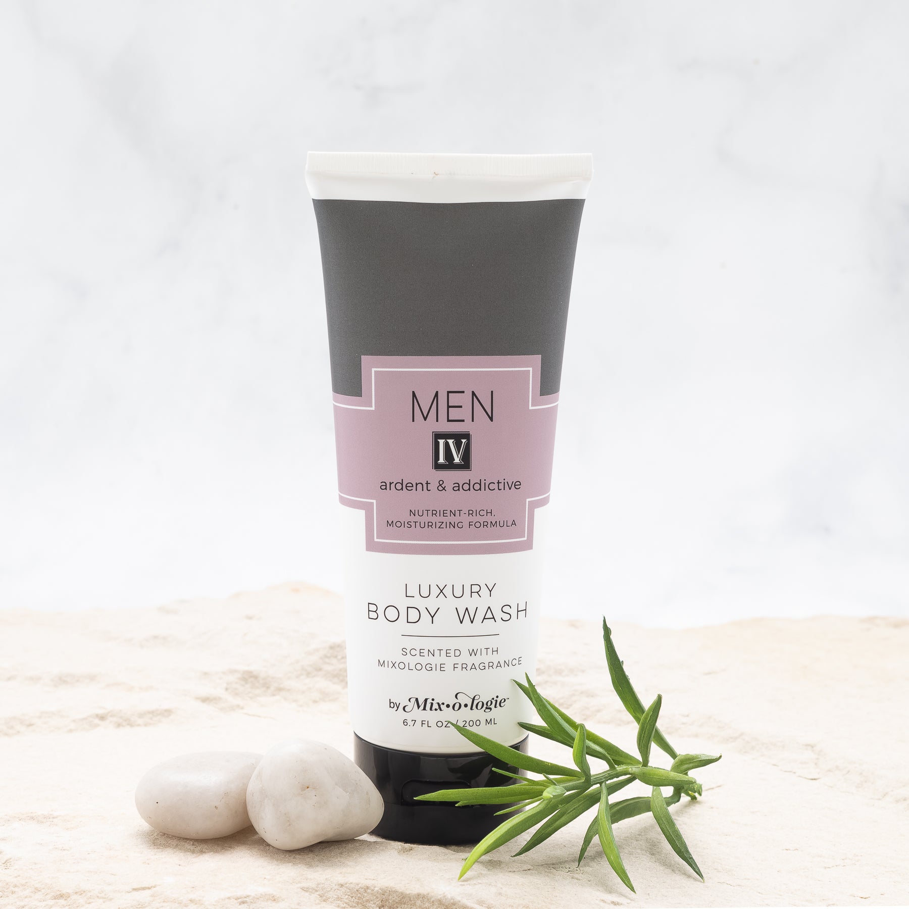 Luxury Body Wash in Men IV (Ardent & Addictive) in grey color package with salmon colored label in sand with rocks and greenery.