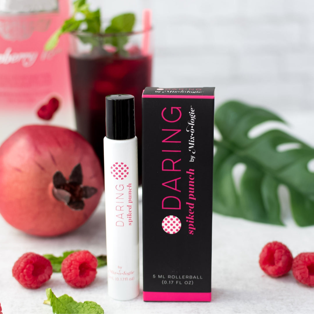 Daring (Spiked Punch) white cylinder rollerball with bright pink color lettering with black box and bright pink color lettering. Rollerball has 0.17 fl oz or 5 mL. Rollerball and rollerball box pictured with pomegranates and raspberries. 