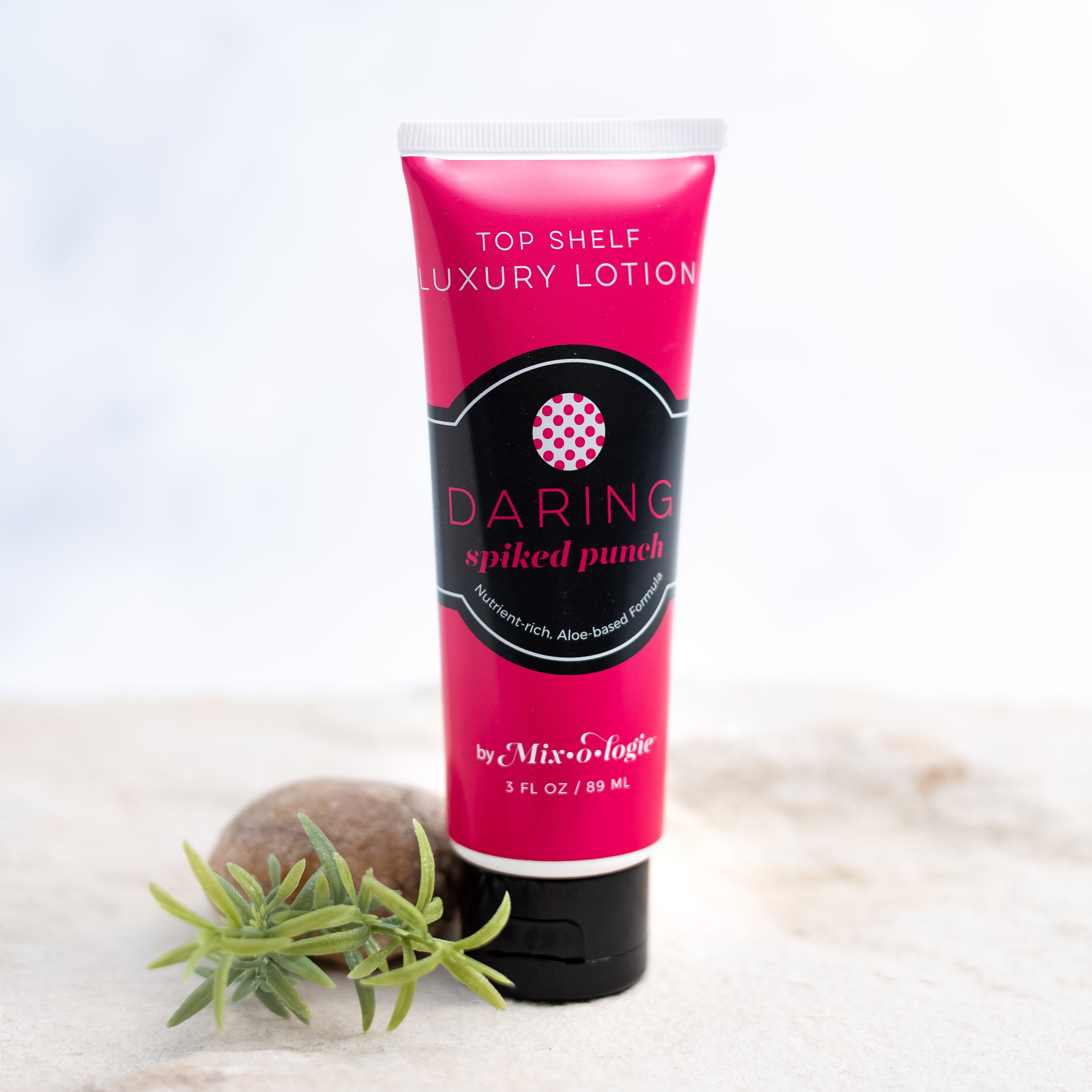 Daring (Spiked Punch) Top Shelf Lotion in bright pink tube with black lid and label. Nutrient rich, aloe-based formula, tube has 5 fl oz or 89 mL. Pictured with white background, sand, rocks, and greenery. 