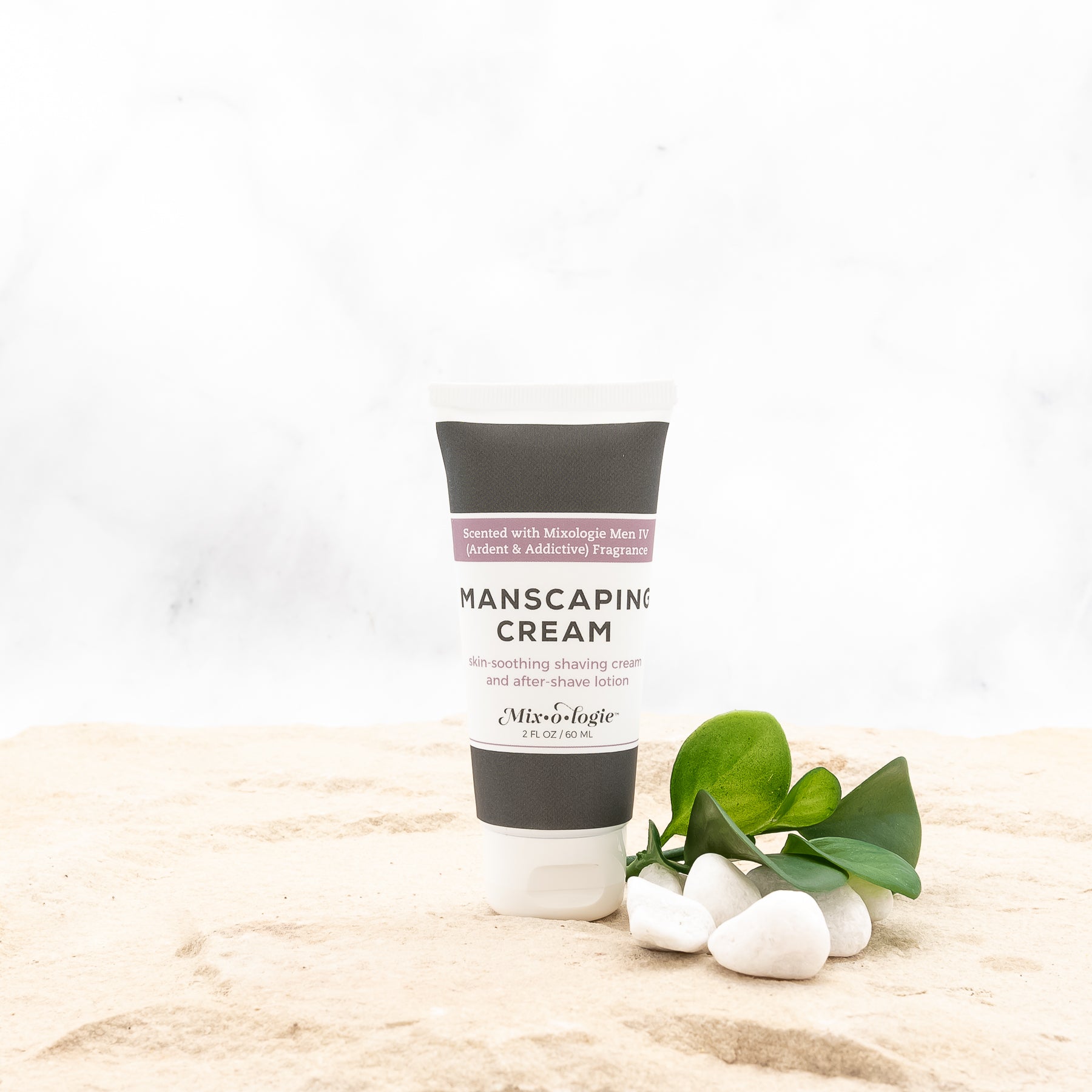 Men’s Manscaping Cream in Men’s IV (Ardent & Addictive) in a black and white tube with salmon colored accents. Skin-soothing shaving cream and after-shave lotion. 2 fl oz or 60 mL. Pictured in sand with rocks and greenery.