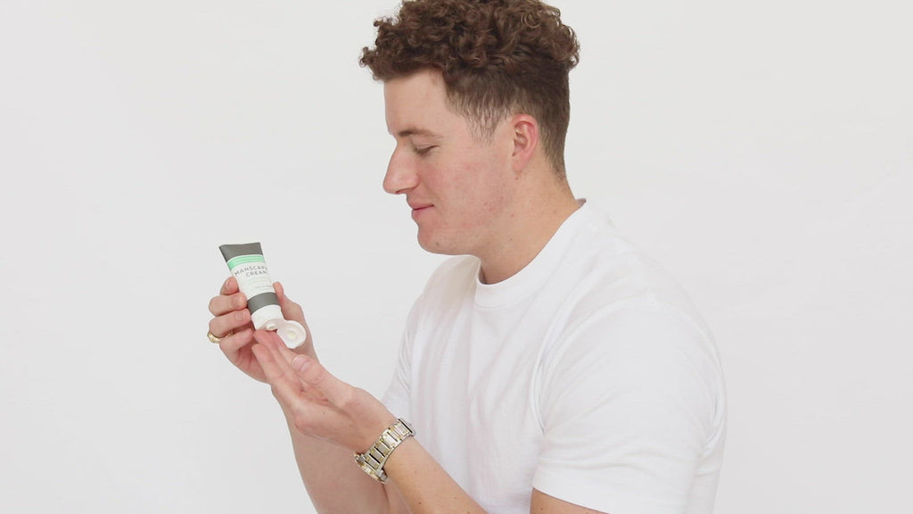 Men’s Manscaping Cream in Men’s I (Timeless & Torrid) in a black and white tube with green accents. Skin-soothing shaving cream and after-shave lotion. 2 fl oz or 60 mL. Pictured in model's hands being applied to face.